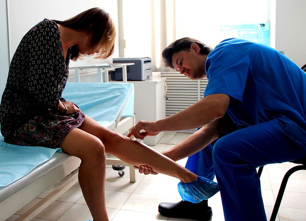 Doctor examining leg with varicose veins